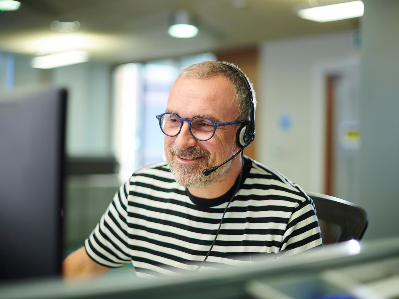 Kundendienstmitarbeiter mit Headset am Bildschirmarbeitsplatz